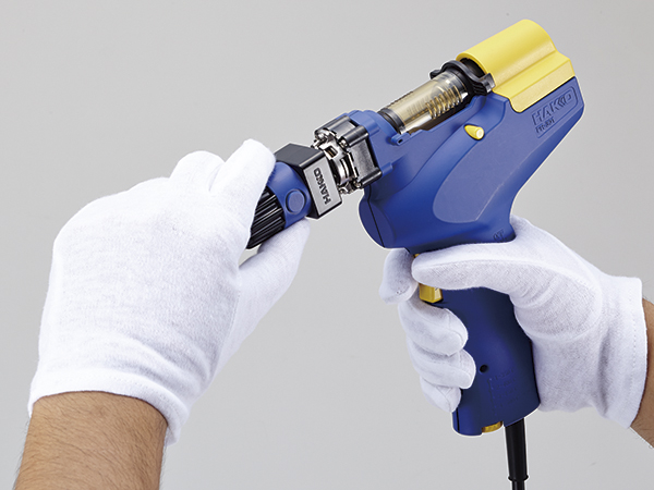 Hakko FR-301 desoldering tip being changed by hand with white gloves